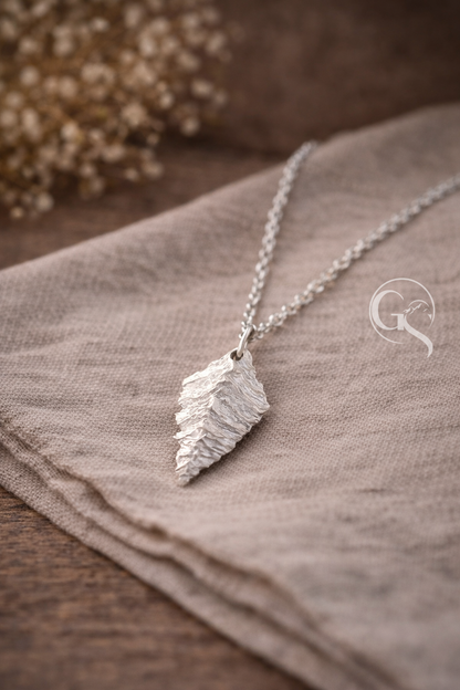 Detailaufnahme eines handgefertigten Silberanhängers aus 999 Silber mit roher Struktur